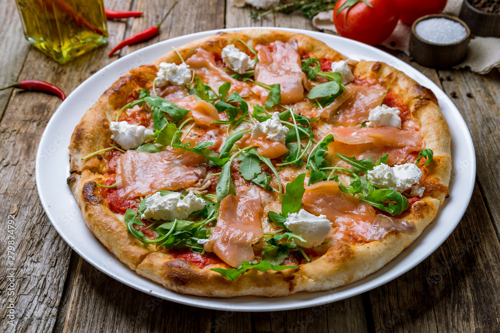 Pizza with salmon and Philadelphia cheese and aragula on wooden table