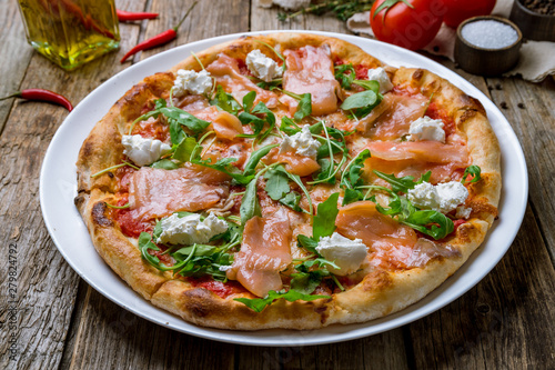 Pizza with salmon and Philadelphia cheese and aragula on wooden table