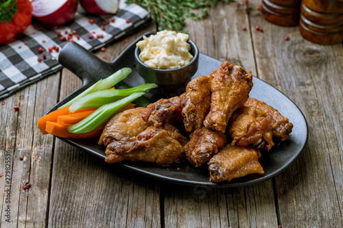 Buffalo chicken wings on black plate on wooden background