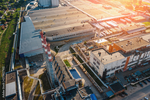 Aerial view of industrial area with warehouses, factory buildings and chimney on foreground at sunset, drone photo © DedMityay