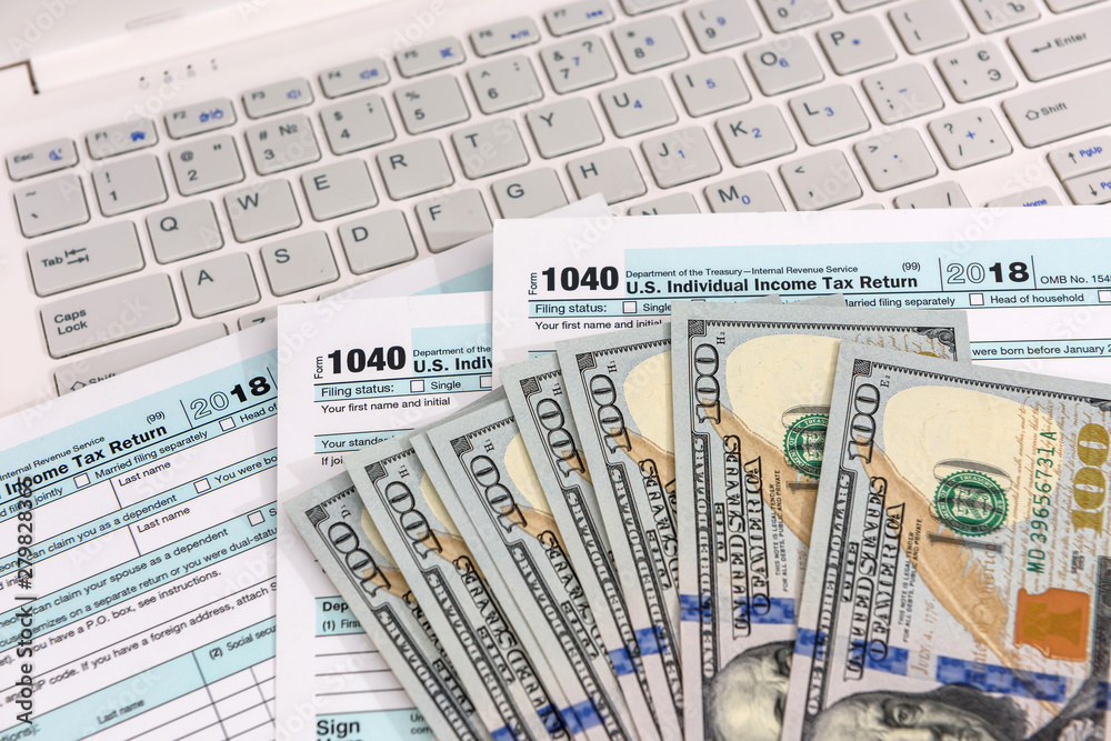 1040 form with laptop and dollar banknotes 1040 form with laptop and dollar banknotes
