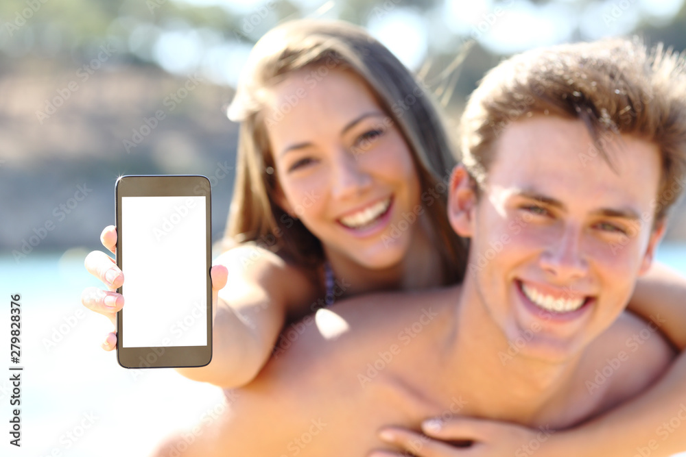 Happy couple on the beach showing blank phone screen