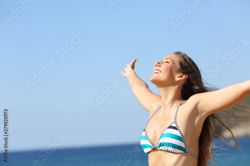 Excited woman in bikini breathing on the beach