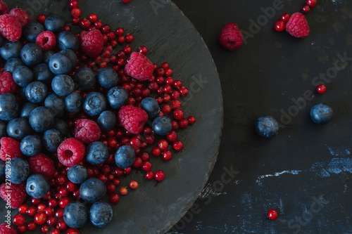 Blueberries, raspberries and recurrants on a black slate dish