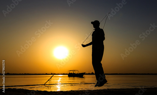 Young Man jumping rope at seaside. silhouetted Man rope skipping in sunset