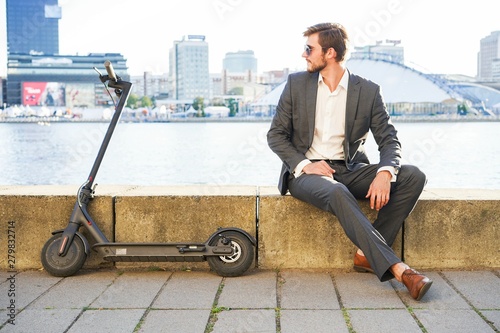 Young modern man using electric scooter on city street. Modern and ecological transportation concept. photo