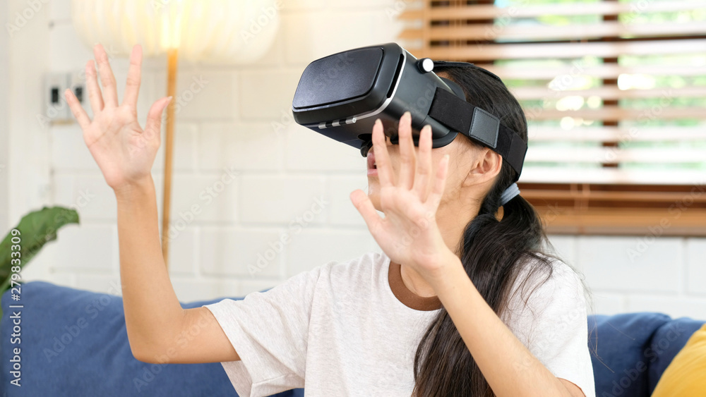 Young asian woman exciting in VR headset looking up and trying to touch objects in virtual reality at home living room, Teenager girl playing VR headset, people and leisure virtual reality technology Young asian woman exciting in VR headset looking up and trying to touch objects in virtual reality at home living room, Teenager girl playing VR headset, people and leisure virtual reality technology