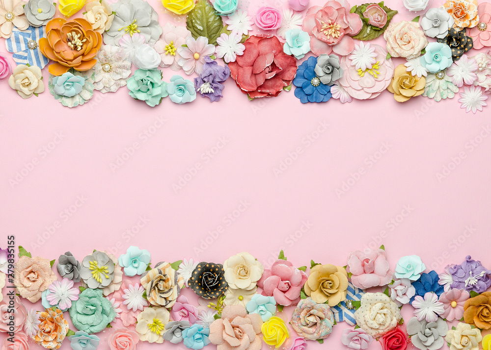 A lot of colorful homemade paper flowers on a pink background. Top view, empty space for text in the center A lot of colorful homemade paper flowers on a pink background. Top view, empty space for text in the center