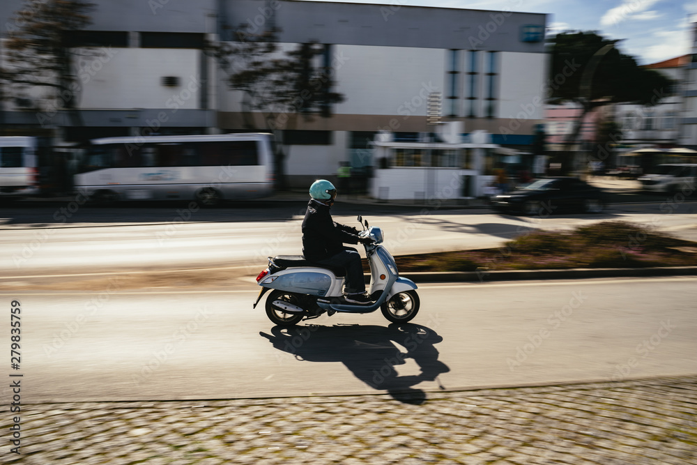 Person riding a motor scooter through town