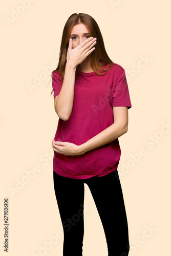 Young redhead girl covering mouth with hands for saying something inappropriate on isolated yellow background