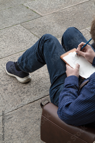 Man sitting on floor drawing on paper notebook