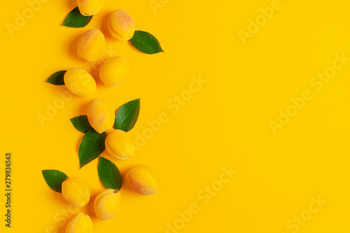 Ripe fresh apricots fruits with green leaves on yellow background. Flat lay, top view, copy space. Fresh organic apricots, diet vegan food. Creative Apricot pattern. Harvest concept