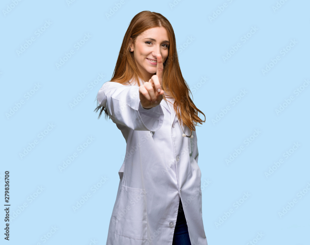 Redhead doctor woman showing and lifting a finger on isolated blue background Redhead doctor woman showing and lifting a finger on isolated blue background