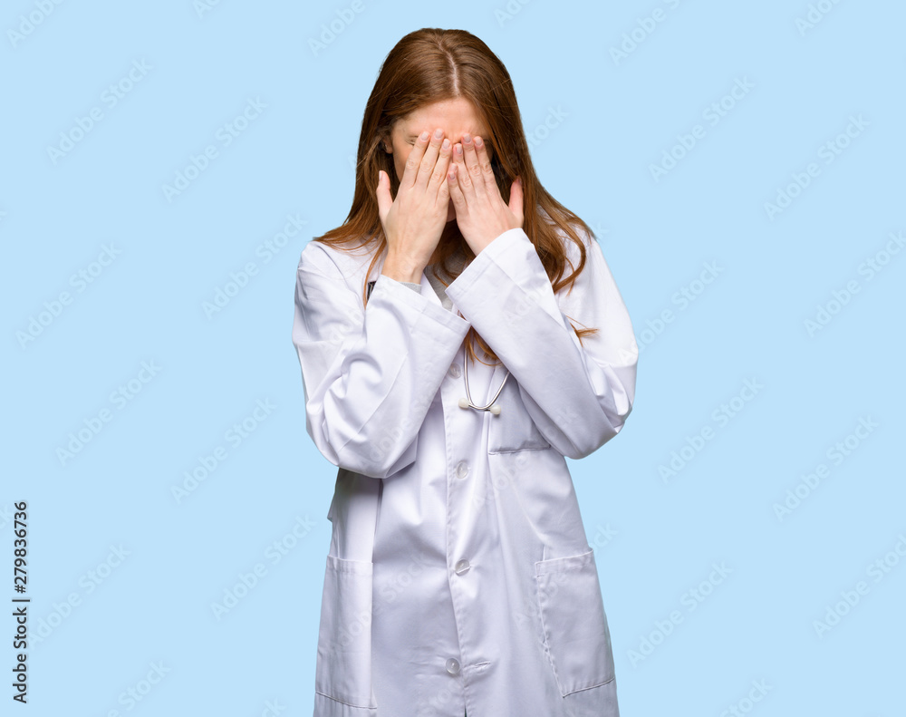 Redhead doctor woman with tired and sick expression on isolated blue background Redhead doctor woman with tired and sick expression on isolated blue background