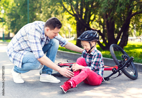 Father is comforting his girl after falling from bicycle