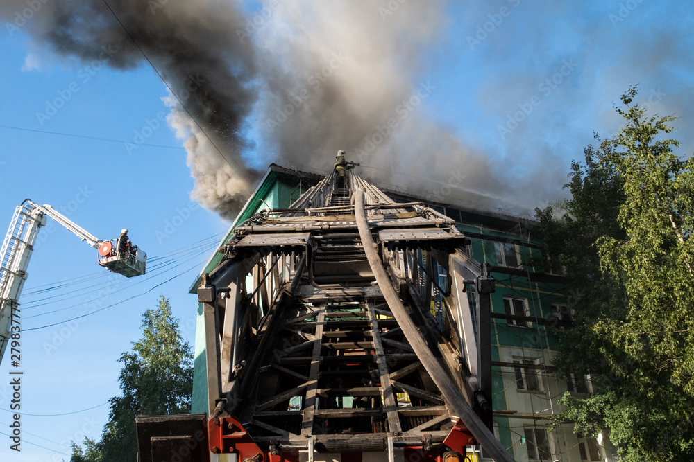 Fototapeta premium Firefighters on the stairs extinguish a fire on the roof of a residential high-rise building. top view