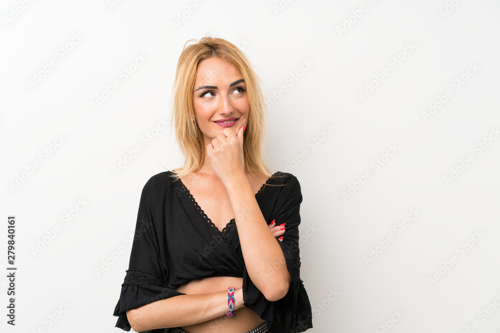 Young blonde woman over isolated white wall looking to the side Young blonde woman over isolated white wall looking to the side