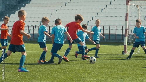 Kids playing soccer on big stadium, dribbling and attacking goal post
