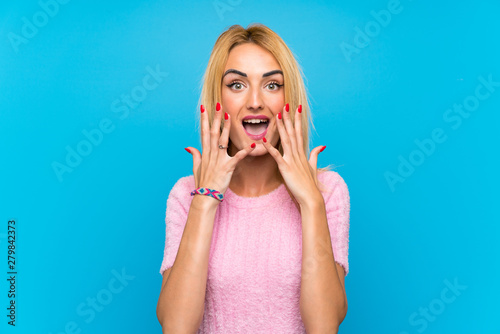 Young blonde woman over blue background with surprise facial expression
