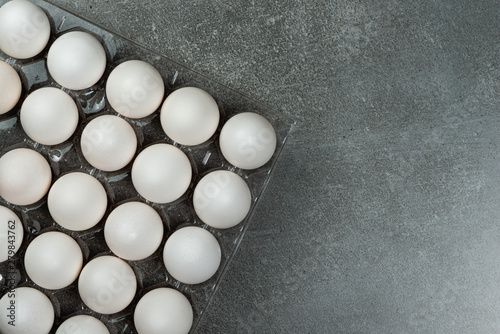 Many white chicken eggs food in the tray box. Gray background space for text.