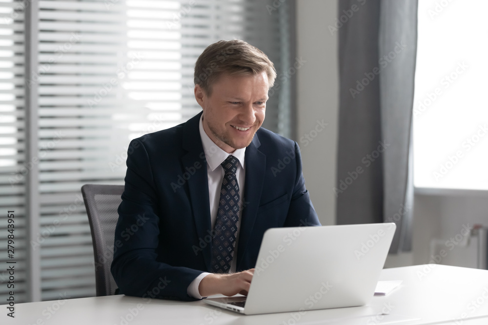 Smiling ceo in suit working on computer sit at desk