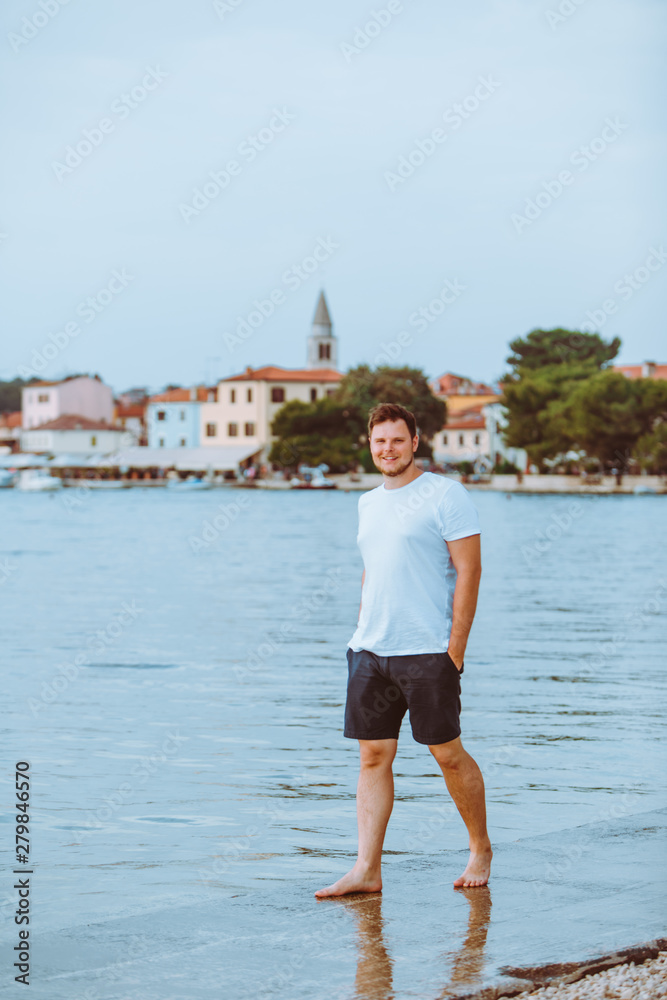 man walking by sea beach in summer evening fazana town on background in croatia