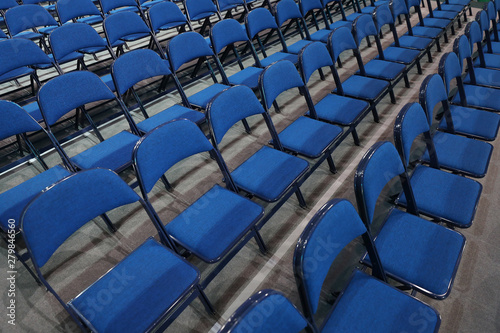 Many blue chairs stand in a row before the event.