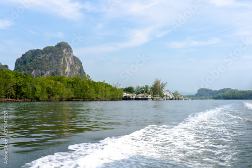 a photo of a beatiful landscape view of a small village with a huge mountain on the background.  This photo is taken by a tourist who is on the boat sailing throughout a long river.