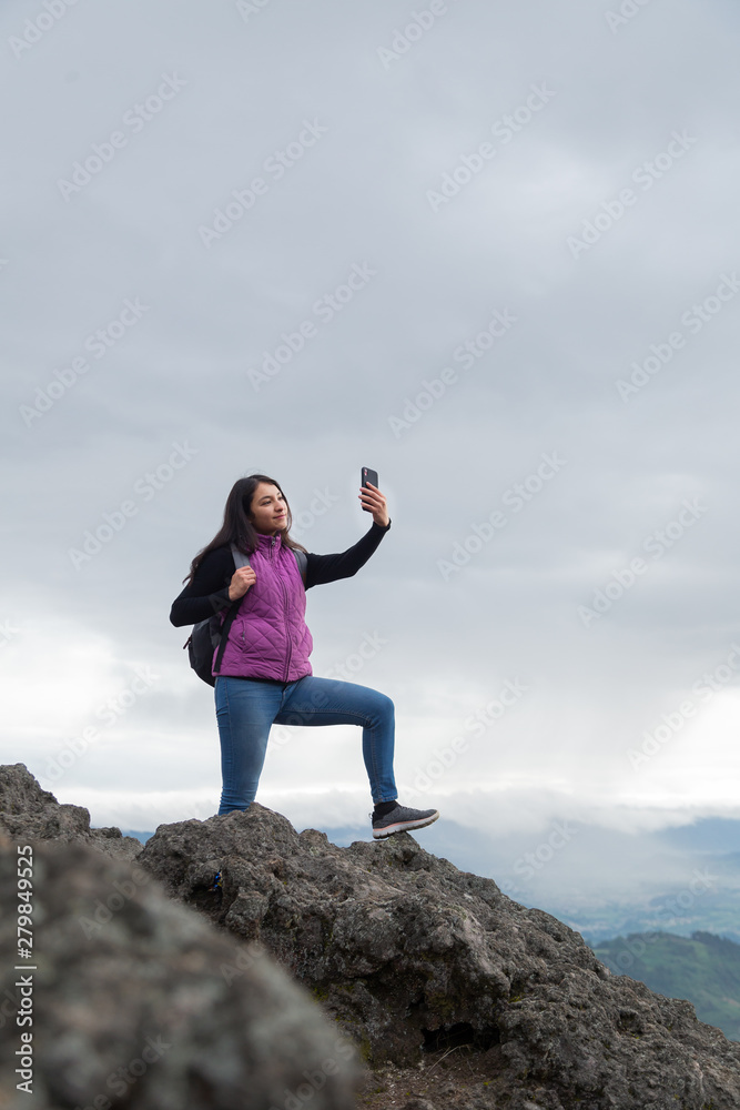 Female tourist traveler taking a selfie on top of the mountain with a spectacular view- woman with technology in the mountain Female tourist traveler taking a selfie on top of the mountain with a spectacular view- woman with technology in the mountain