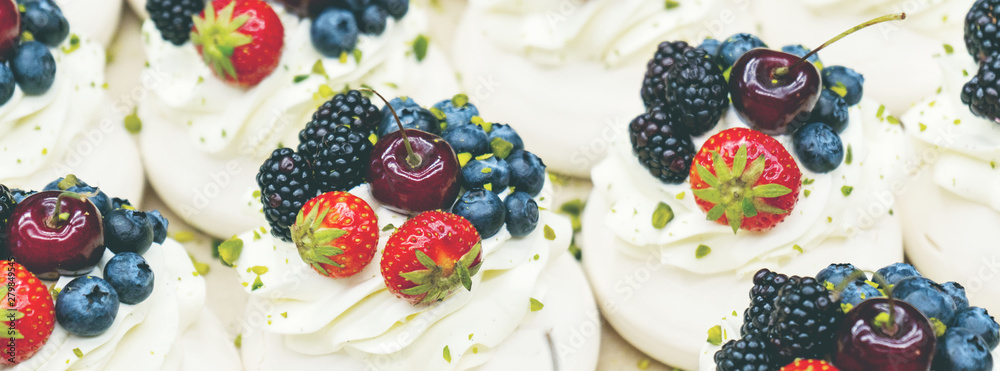 Pavlov cakes with fresh berries and cream. Lie in rows on a baking sheet in the confectionery shop. Pavlov cakes with fresh berries and cream. Lie in rows on a baking sheet in the confectionery shop.