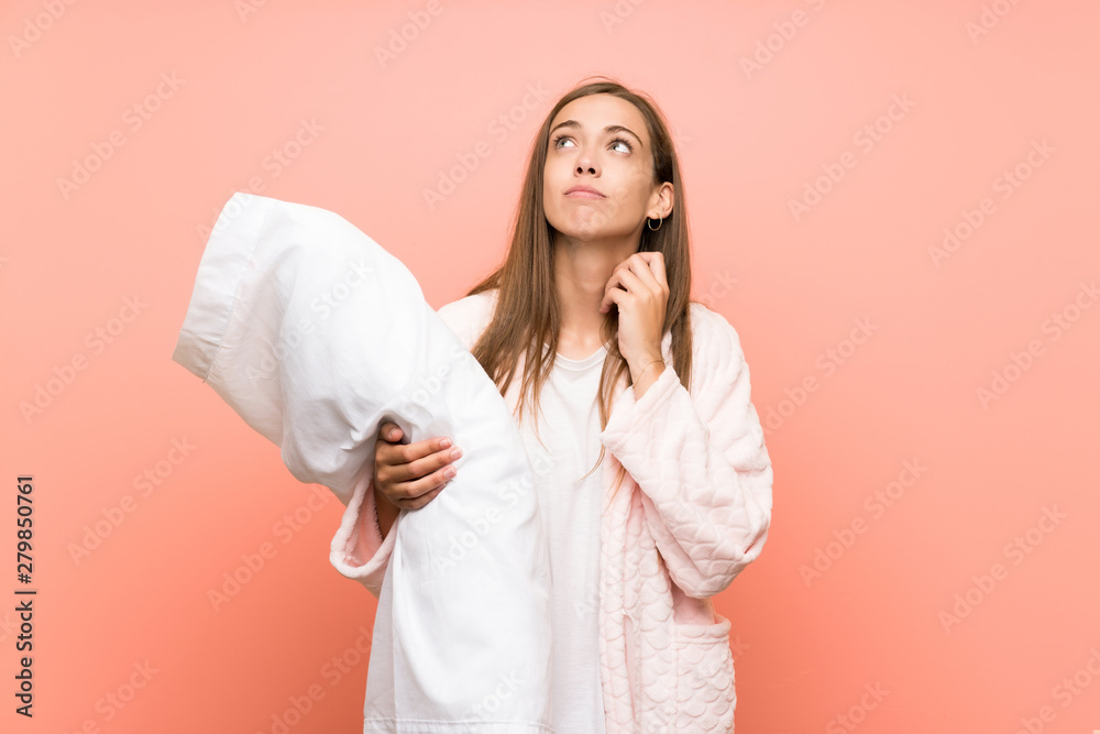 Young woman in dressing gown over pink wall thinking an idea Young woman in dressing gown over pink wall thinking an idea