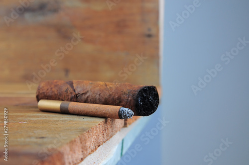Burning handmade luxury Cuban cigar on an old wooden background with copyspace