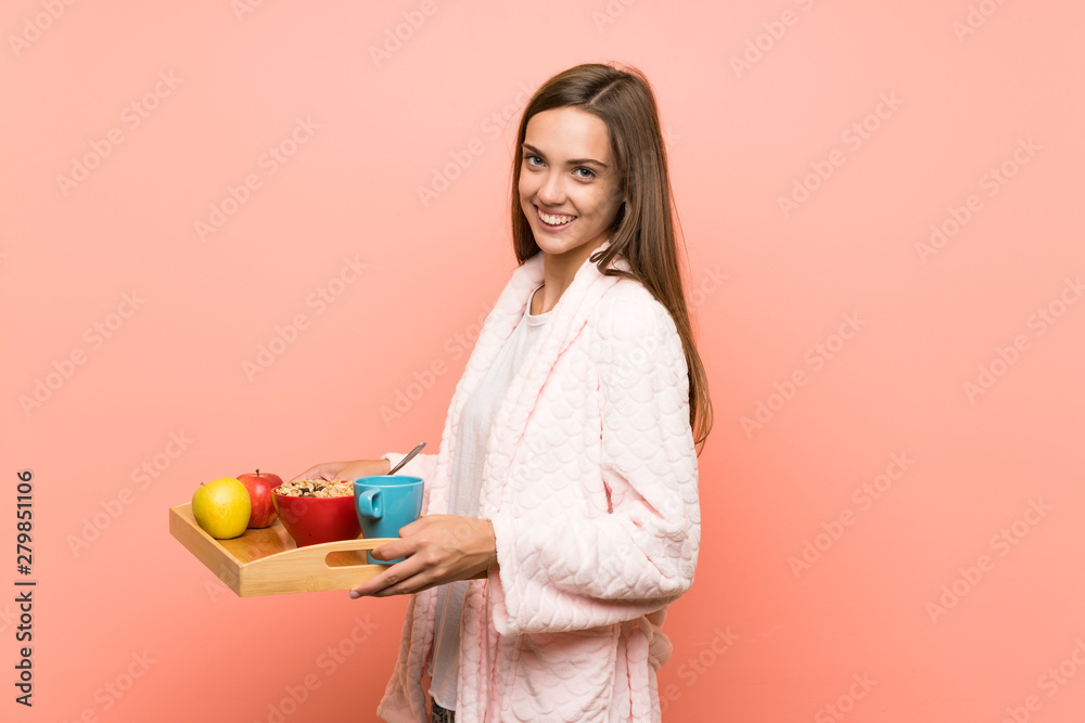 Happy Young woman in dressing gown over pink wall with breakfast Happy Young woman in dressing gown over pink wall with breakfast