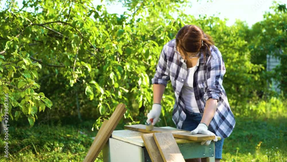 crafts woman processing old wooden plank with metal brush in sunny garden crafts woman processing old wooden plank with metal brush in sunny garden