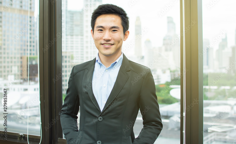 An asian business man is standing beside the window An asian business man is standing beside the window