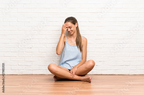 Young woman sitting on the floor laughing © luismolinero