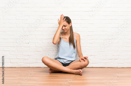 Young woman sitting on the floor having doubts with confuse face expression