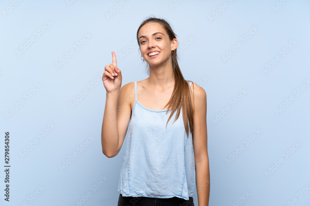 Young woman over isolated blue background showing and lifting a finger in sign of the best Young woman over isolated blue background showing and lifting a finger in sign of the best