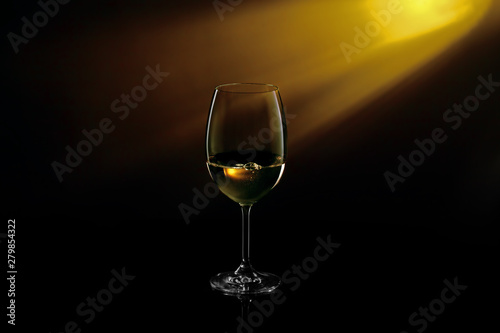 Glass of white wine on black to yellow background. Concept studio shot.