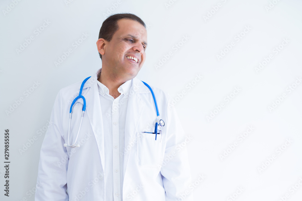 Middle age doctor man wearing stethoscope and medical coat over white background looking away to side with smile on face, natural expression. Laughing confident. Middle age doctor man wearing stethoscope and medical coat over white background looking away to side with smile on face, natural expression. Laughing confident.