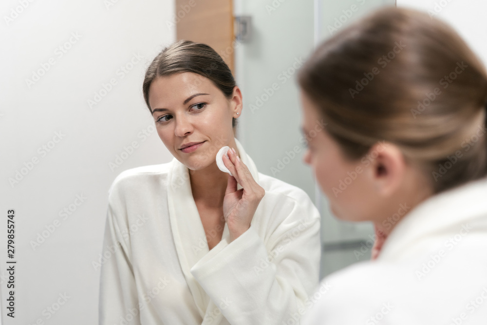Woman in white bathrobe holding cotton pad in hands Woman in white bathrobe holding cotton pad in hands