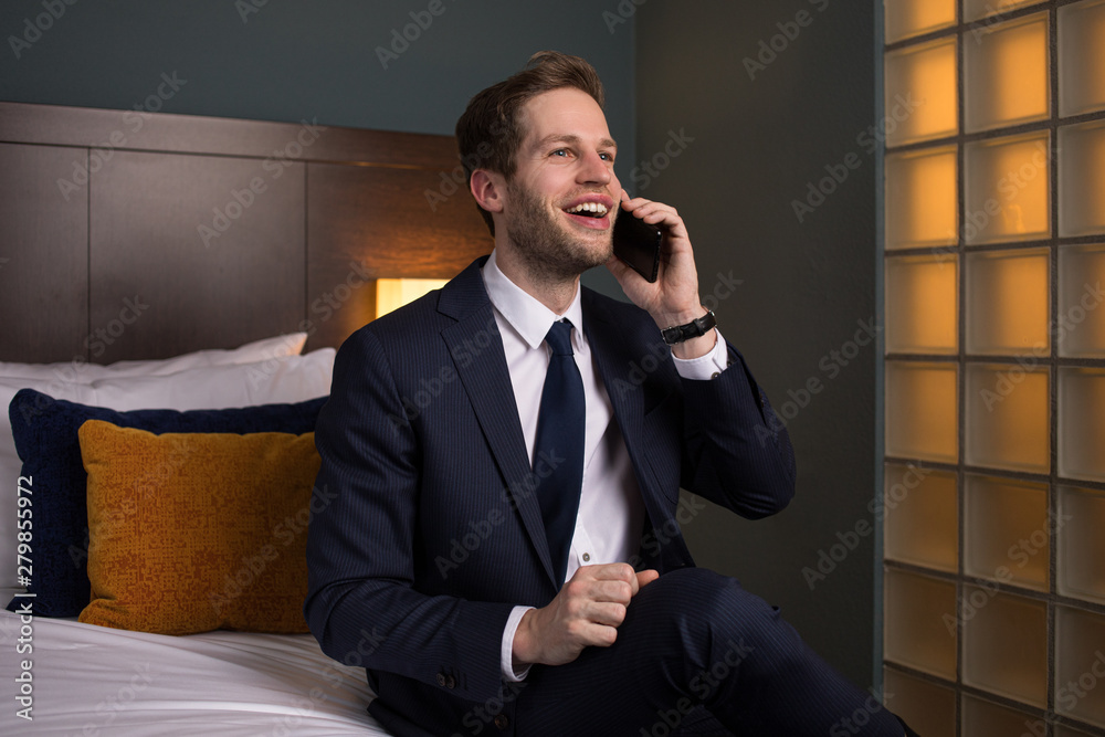 Junger Geschäftsmann telefoniert im Hotelzimmer mit seinem Smartphone Junger Geschäftsmann telefoniert im Hotelzimmer mit seinem Smartphone