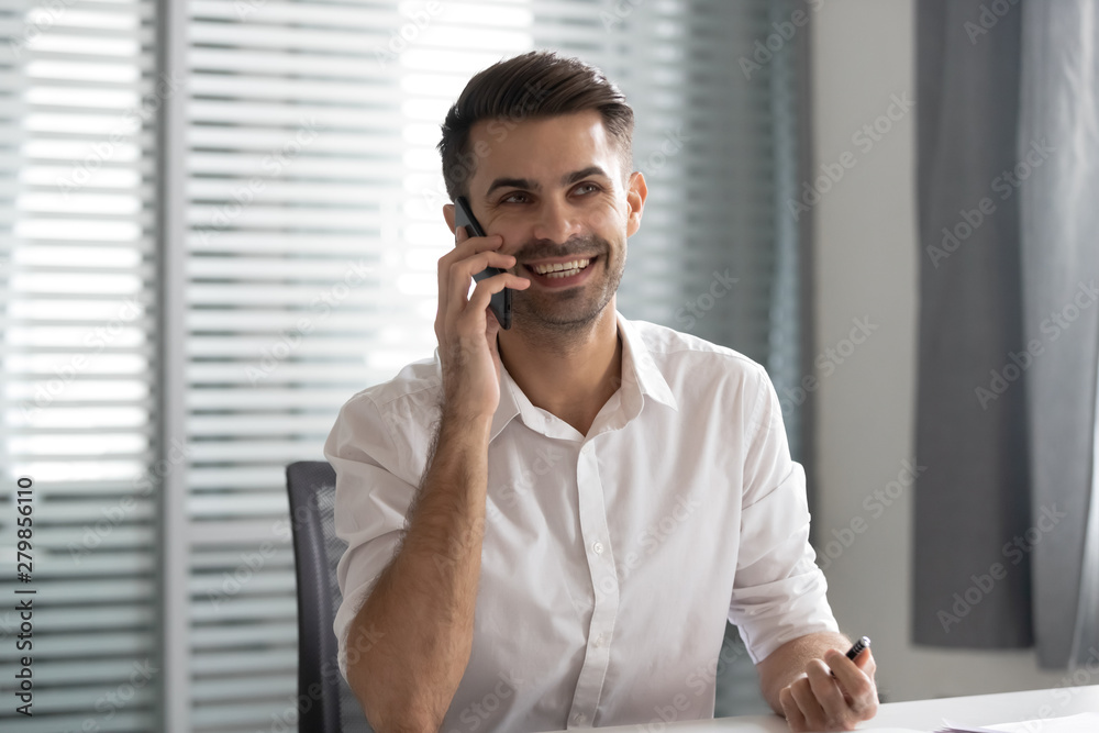 Smiling businessman talking on phone making business call in office Smiling businessman talking on phone making business call in office