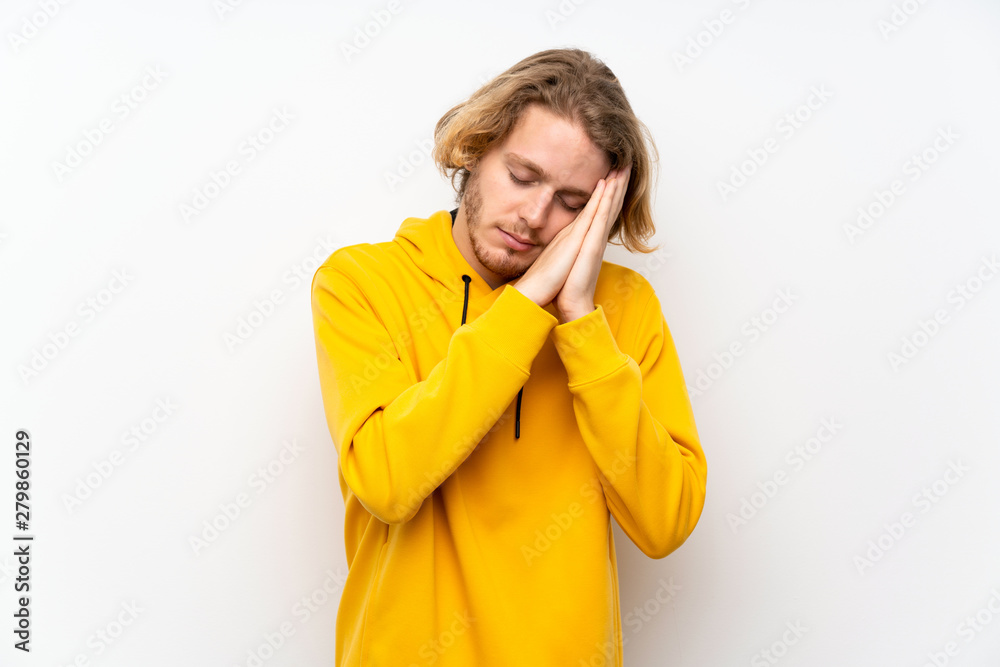 Blonde man with sweatshirt over white wall making sleep gesture in dorable expression Blonde man with sweatshirt over white wall making sleep gesture in dorable expression