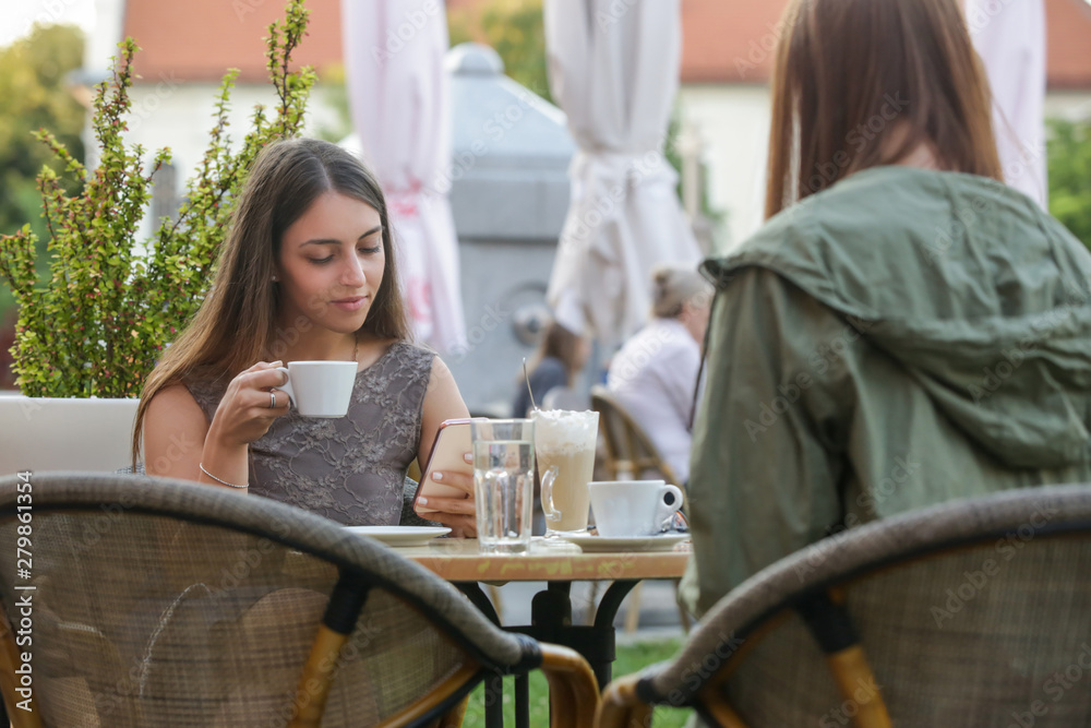 Two young women drinking coffee in the street cafe, casual lifestyle concept