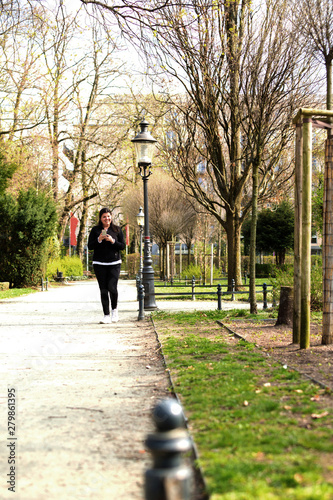 Lady chats on the phone outside while walking in a city square