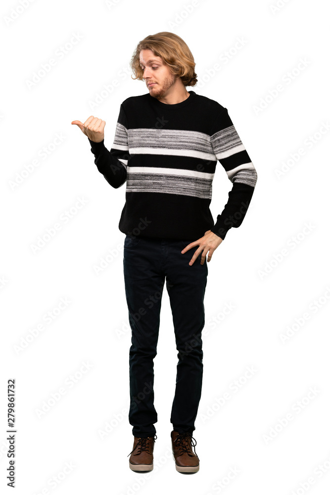Full-length shot of Blonde man unhappy and pointing to the side over isolated white background Full-length shot of Blonde man unhappy and pointing to the side over isolated white background