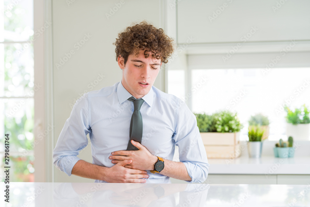 Young business man wearing a tie with hand on stomach because indigestion, painful illness feeling unwell. Ache concept. Young business man wearing a tie with hand on stomach because indigestion, painful illness feeling unwell. Ache concept.