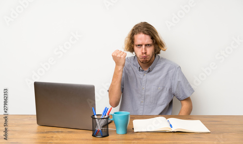 Blonde man with a laptop with angry gesture © luismolinero