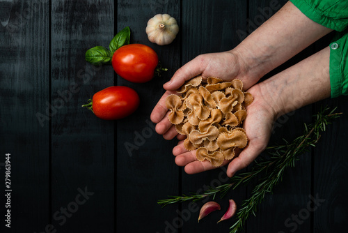 Bild auf Leinwand Model holding farfalle pasta semolina on black pinus background